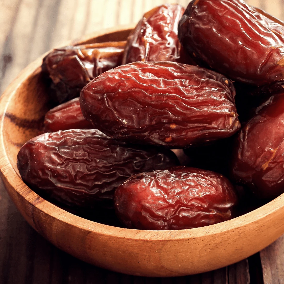 A wooden bowl of soft, glossy dates